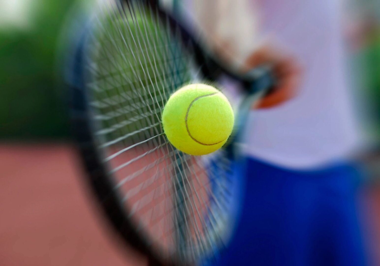 A tennis ball is in the air with a racket.