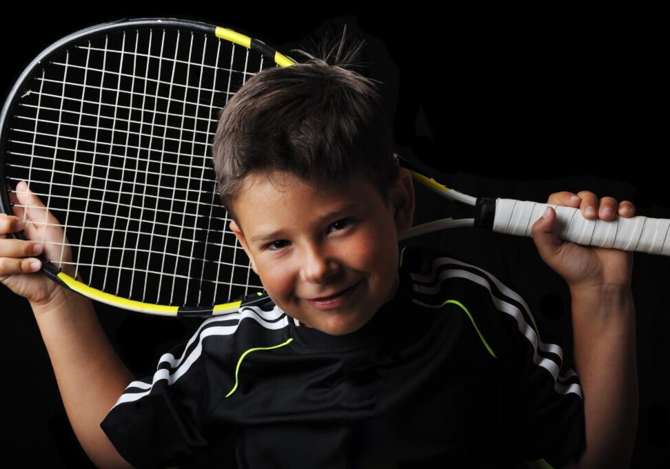 A young boy holding a tennis racket in his hands.